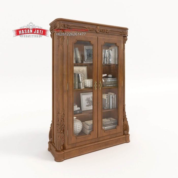 Tampilan penuh dari sudut perspektif atas lemari hias jati mewah seri Gloucester 2 pintu kaca terisi penuh buku dan pajangan dekorasi produk Hasan Jati Furniture.