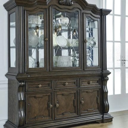 Tampilan penuh lemari hias jati mewah seri Maylee 3 pintu kaca warna cokelat gelap dihiasi pajangan cangkir porselen di dalam ruang makan produk Hasan Jati Furniture.