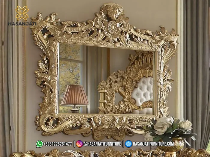 Bingkai cermin dinding gantung dengan ukiran mahkota rimbun warna emas mewah seri Bernadette memantulkan visual dipan kasur produk Hasan Jati Furniture.