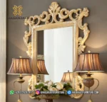 Bingkai cermin dinding gantung ukir mewah tipe Rowena duco dipadukan dengan sepasang lampu meja kap cokelat produk Hasan Jati Furniture.