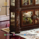 Detail pintu kaca bagian bawah lemari jati Vendome dengan tarikan kuningan bulat besar medallion dan struktur kaki decorative bun feet.