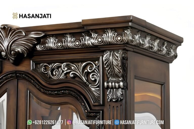 Close up detail kehalusan seni pahat tangan manual berhiaskan warna silver leaf pada mahkota atas dan kepala pilar lemari hias jati Promenade Jepara.