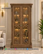 Lemari hias jati mewah seri Aurelia 2 pintu kaca lampu LED menyala di ruang tamu produk Hasan Jati Furniture.