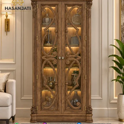 Lemari hias jati mewah seri Aurelia 2 pintu kaca lampu LED menyala di ruang tamu produk Hasan Jati Furniture.