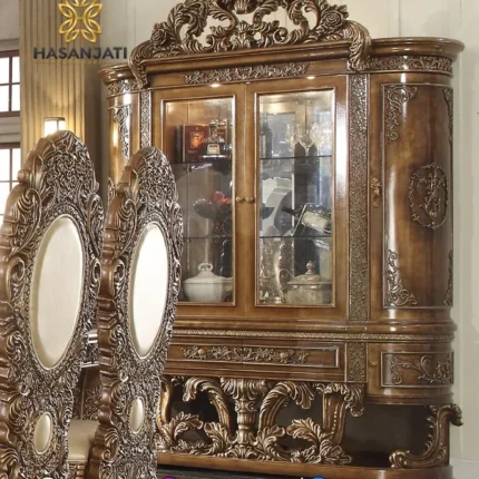 Penempatan lemari pajangan kristal mewah Constantine di belakang kursi makan ukir berlatar interior ruang makan klasik eropa.