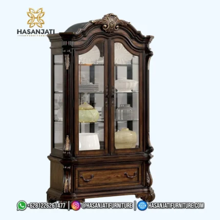Tampilan penuh tampak depan lemari pajangan kristal seri Leovanni dari kayu jati memperlihatkan susunan 1 laci horizontal besar bawah berlatar putih polos.