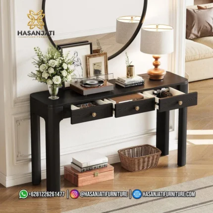 Meja konsol jati warna hitam seri Solstice 3 laci terbuka dihiasi vas bunga putih berlatar cermin bulat besar.