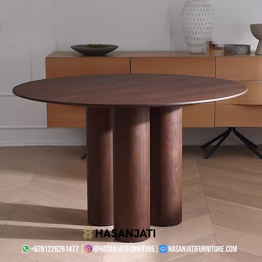 Meja makan minimalis berbentuk bundar dari kayu jati solid berwarna cokelat tua dengan desain kaki silinder, menampilkan kesan modern dan elegan.