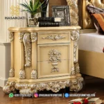 Tampilan close up nakas lampu tidur laci dari set kamar tidur mewah seri Rowena cat duco dengan ornamen ukiran bunga berlapis perak produk Hasan Jati Furniture.