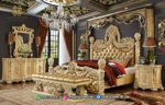 Set kamar tidur mewah seri Rowena Luxury Gold lengkap dengan dipan kasur emas, bench, sepasang nakas duco, lampu gantung kristal, dan meja rias produk Hasan Jati Furniture.